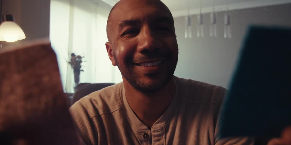 A man is smiling and holding up two pieces of fabric