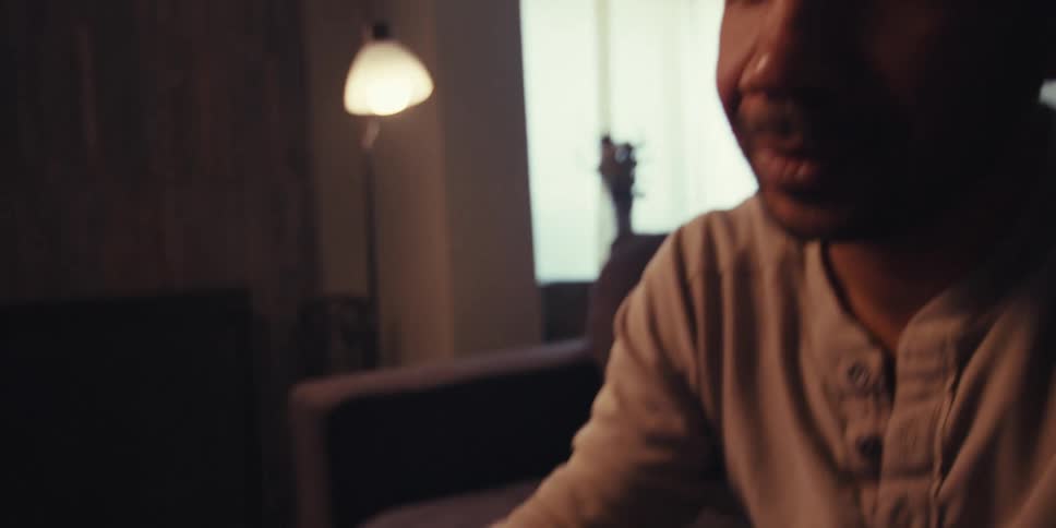 A man is seated in front of a laptop looking at fabric swatches