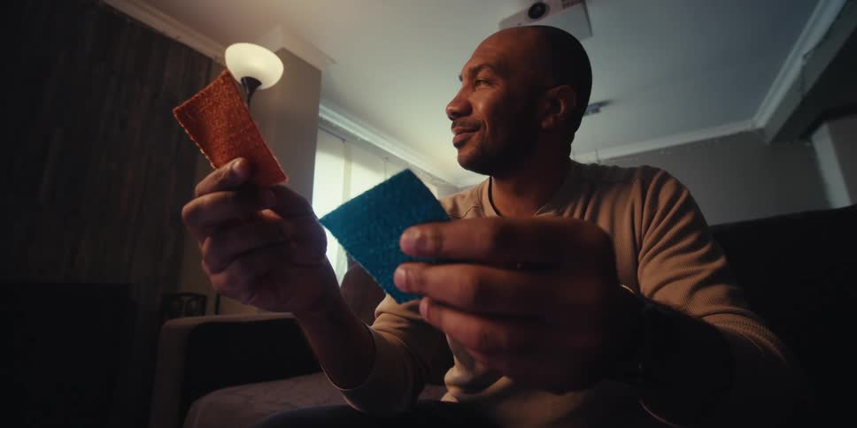 A man is nods while holding two pieces of fabric