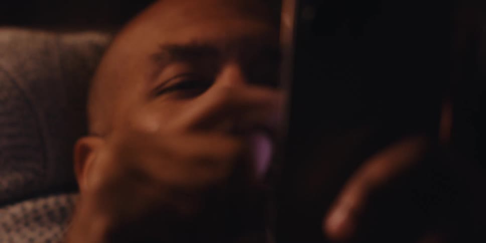 A man is scrolling on his phone in bed