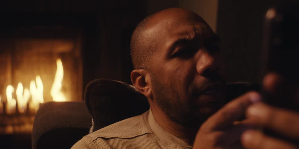 Man relaxing near fireplace having a conversation via face time on cell phone