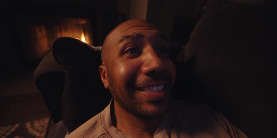 Man looking at a cell phone lying on the sofa and after a while he moves his arm because he is pleased with something he saw