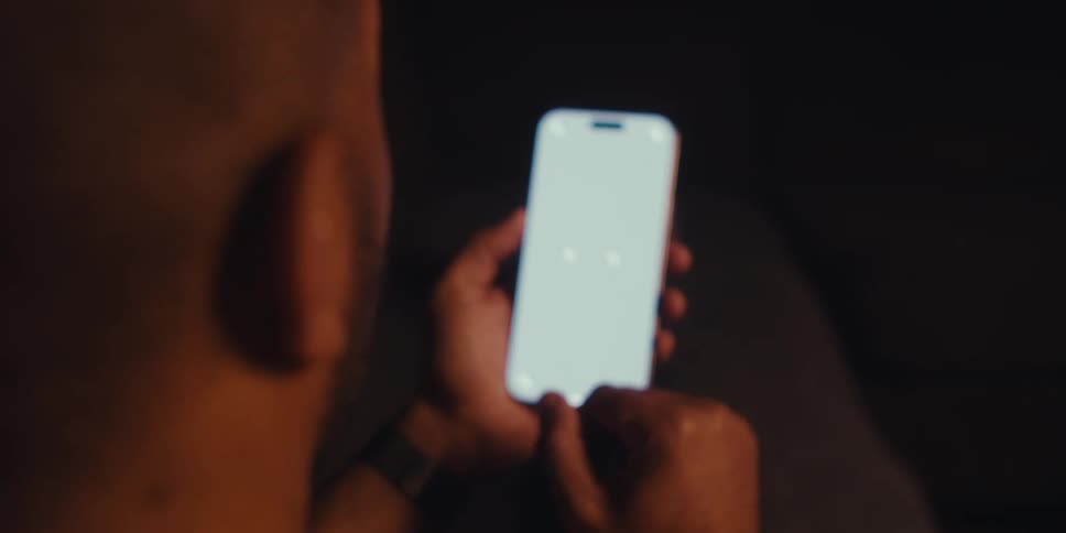 A man is shown from the back holding and interacting with a smartphone