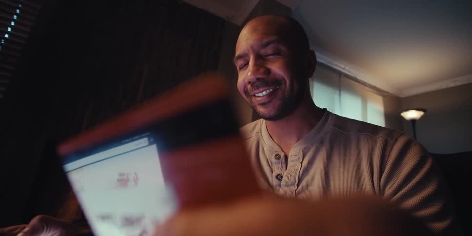 Portrait of a happy man holding a credit card while scrolling on his phone