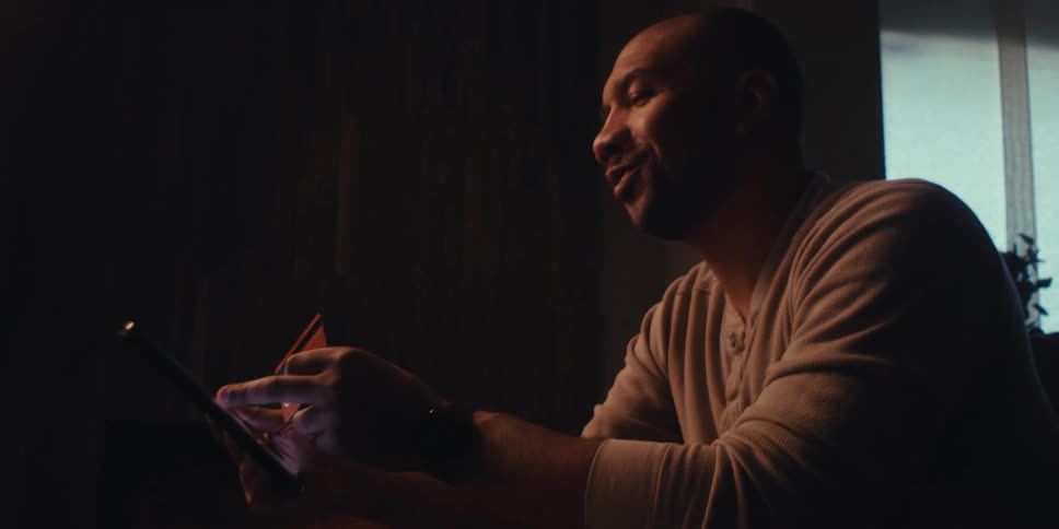 Man sitting holding a credit card and a tablet