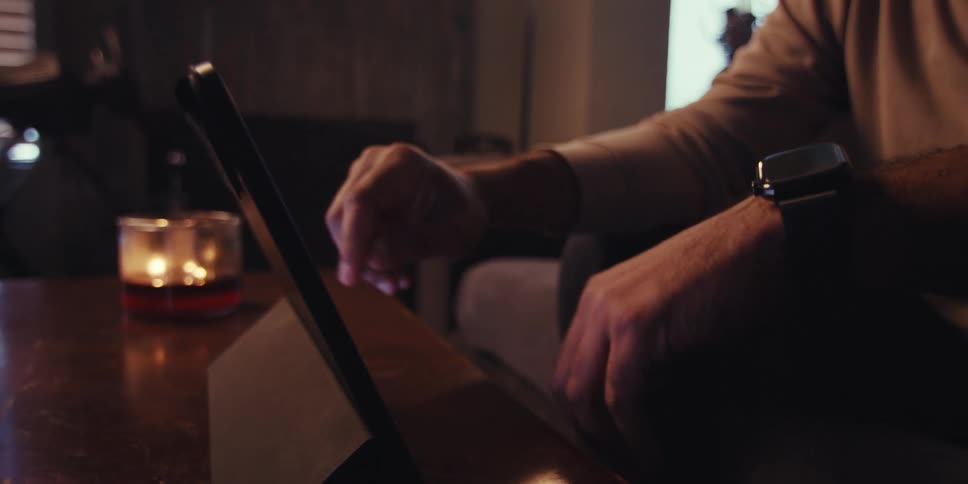 Man sitting in a living room manipulates a tablet