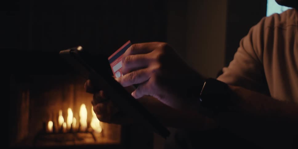 Man holding a credit card typing something on a tablet