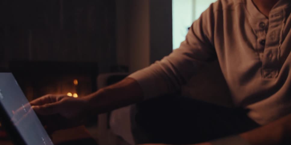 Man sitting on a sofa typing on a tablet and smiling