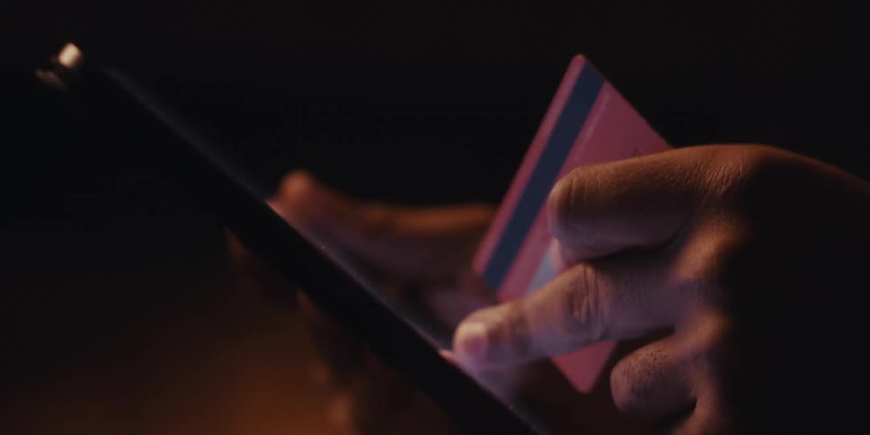 A black man enters numbers from a credit card into an electronic tablet