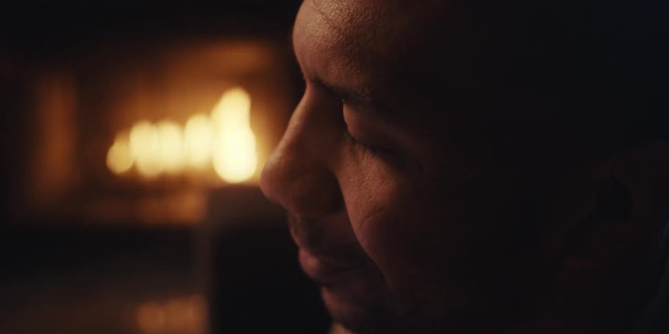 Side portrait of a happy man with a lit fireplace in the background