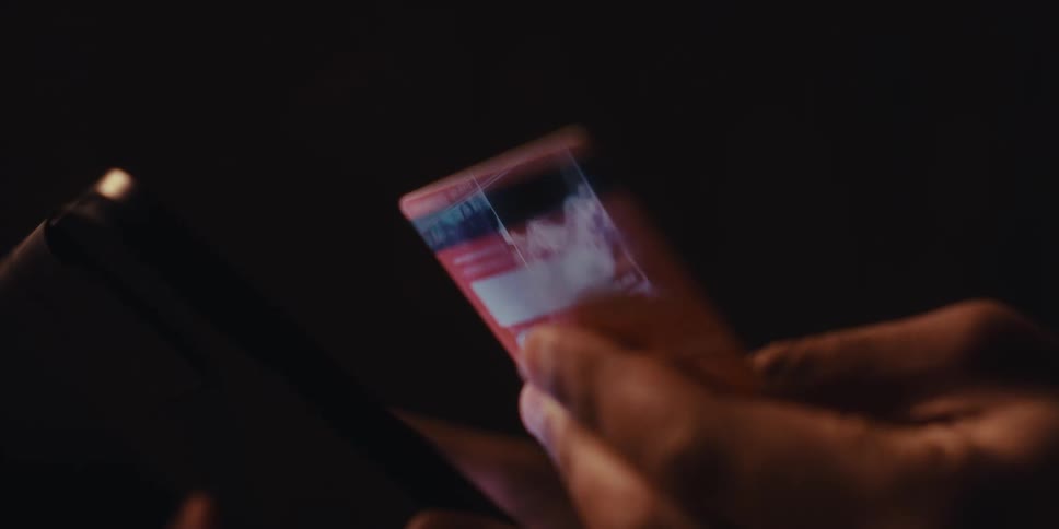 Woman scrolls on a device while holding a card that reflects the shopping site she is browsing