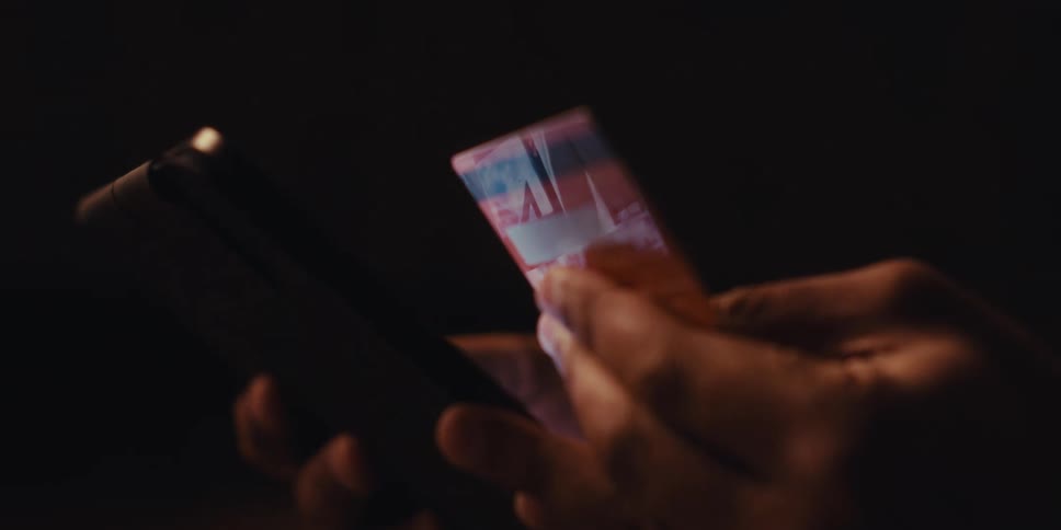 Close up of a persons hands holding a red credit card next to a tablet