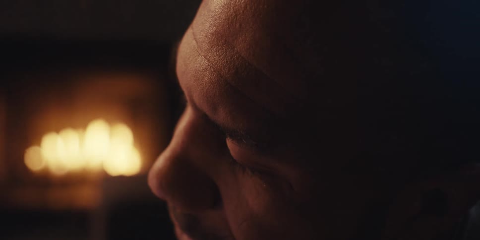 Side portrait of a man with a lit fireplace in the background