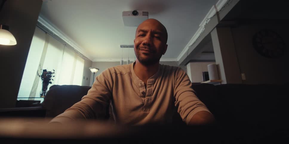 A man smiles as he sits back and types on his tablet
