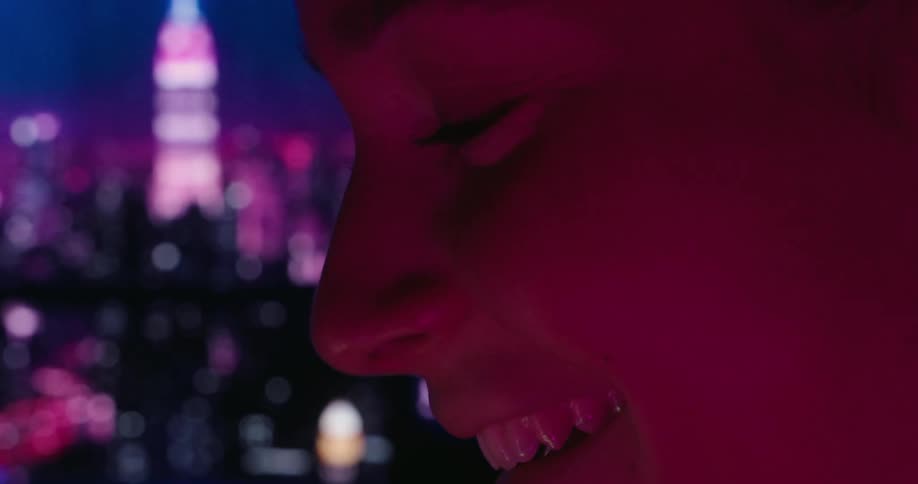 A woman is smiling with a lit up city as her backdrop