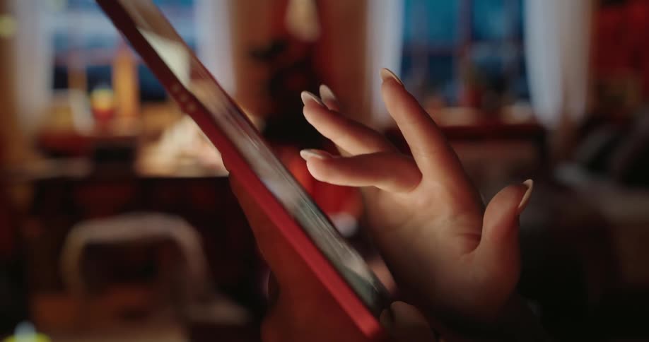 A persons finger scrolling down a tablet screen and their nails are painted in white