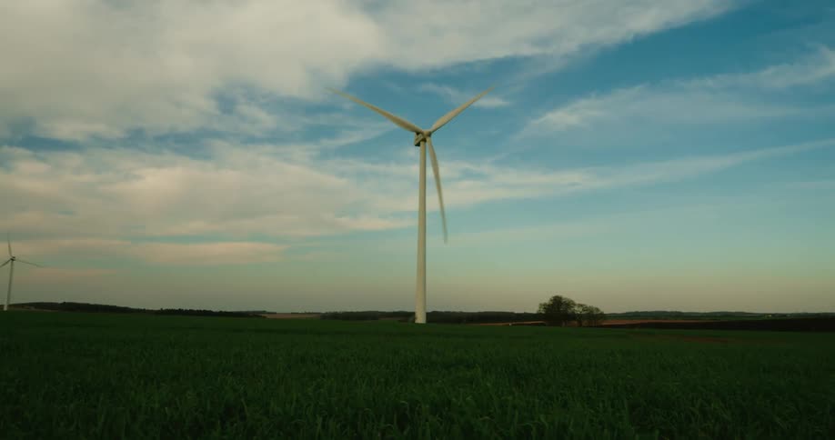 A large industrial windmill in a field turns with the wind