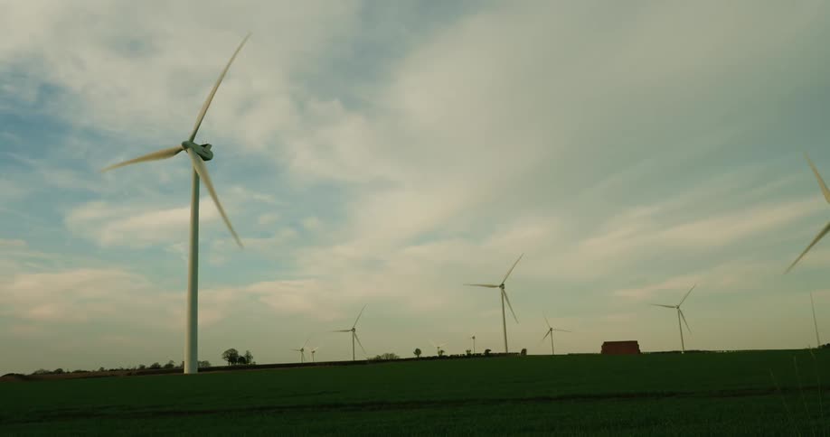 Tall windmills spin with the wind on the field
