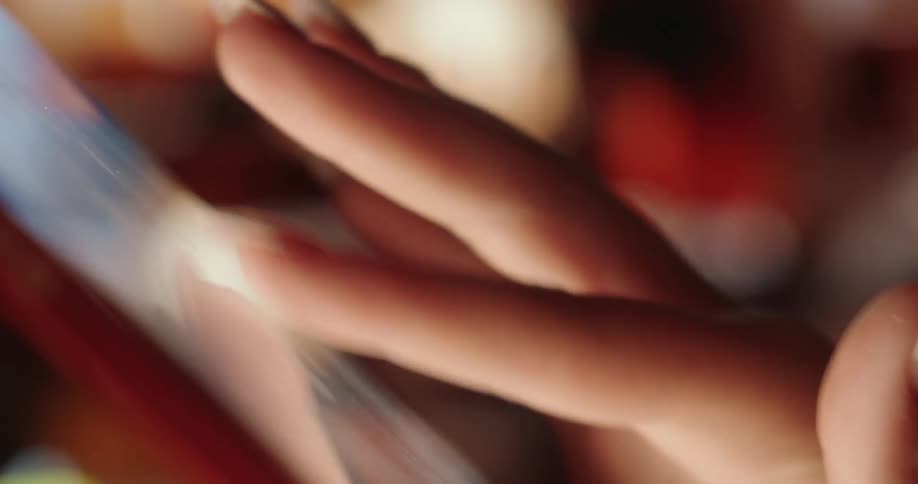 The fingers of a person touching and scrolling a bright phone screen