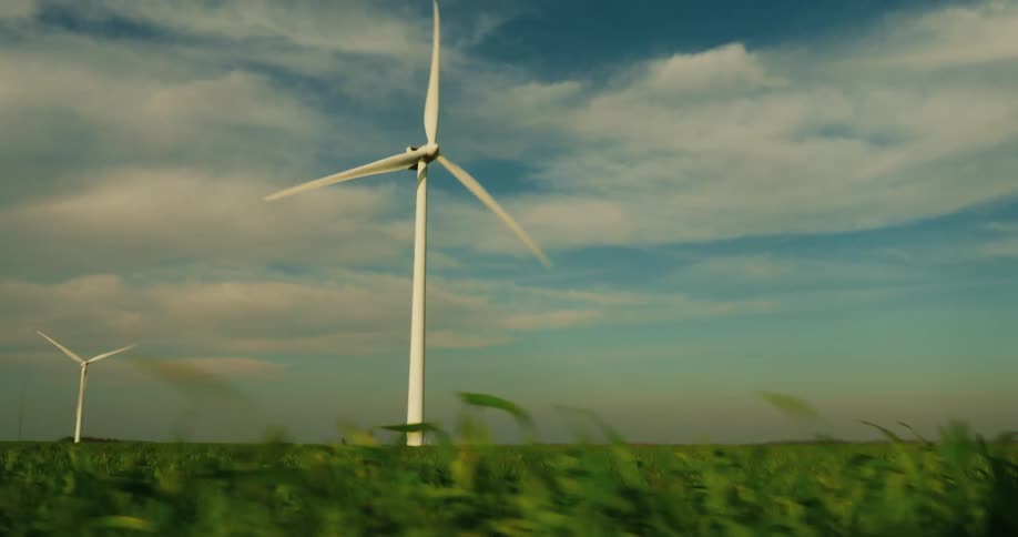 Wind turbine blade being shot from a moving car in a grassy field