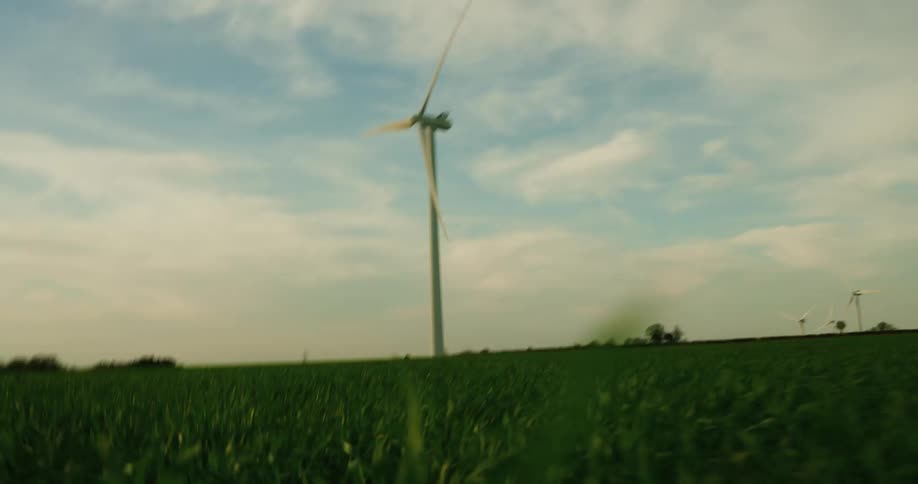 A lone wind turbine stands tall in a field of green grass under a cloudy sky