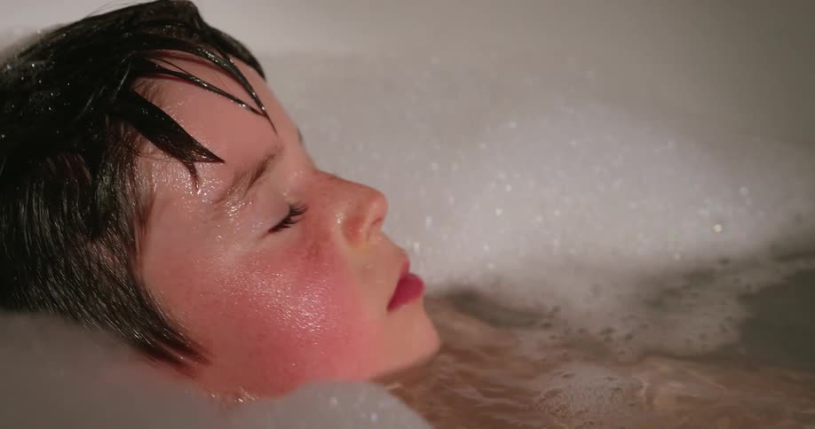 Child soaking in a bathtub full of foam