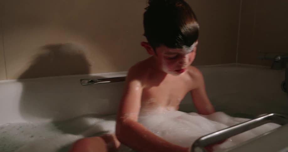 Child taking a bath playing with foam in the tub