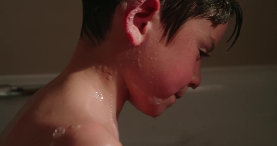 Boy taking a bath and putting water on his face