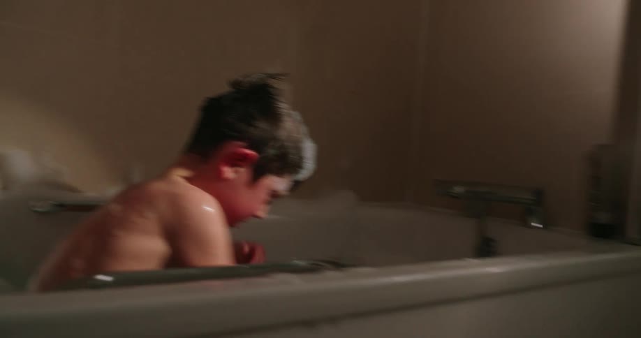 A boy is splashing in the tub