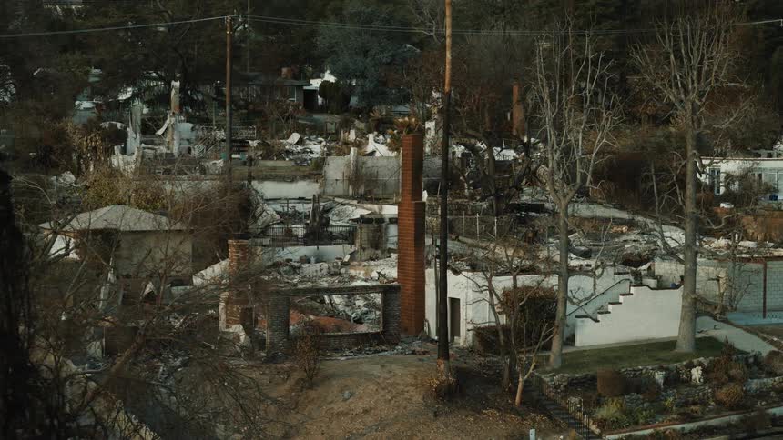 From atop a hill charred remains of a neighborhood are shown in the aftermath of a devastating wildfire leaving only ruins and chimneys behind