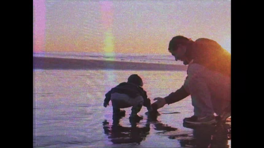 A father and son are digging in the wet sand on the beach