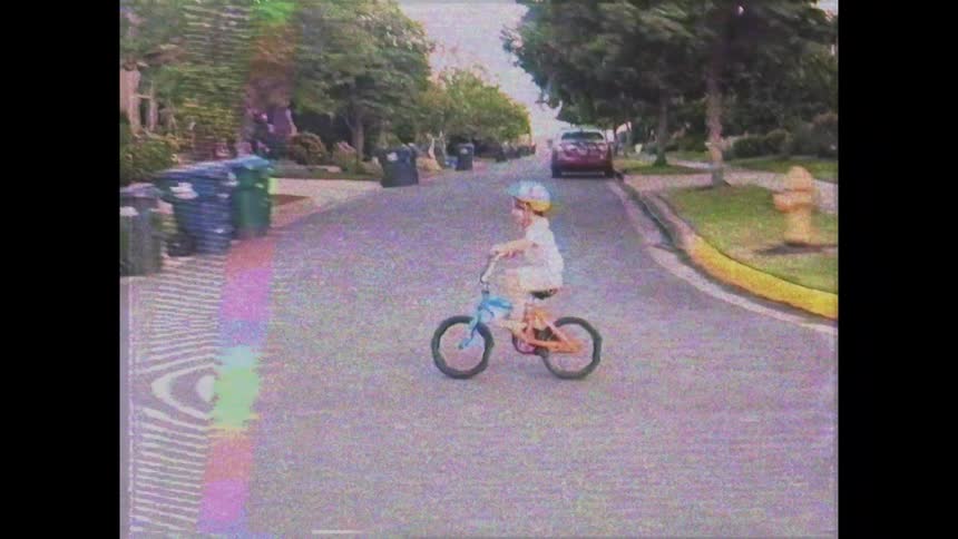 A child is riding his bicycle on the sidewalk