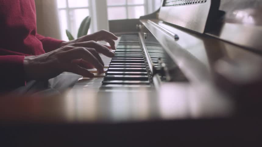 A man is sitting as he plays piano