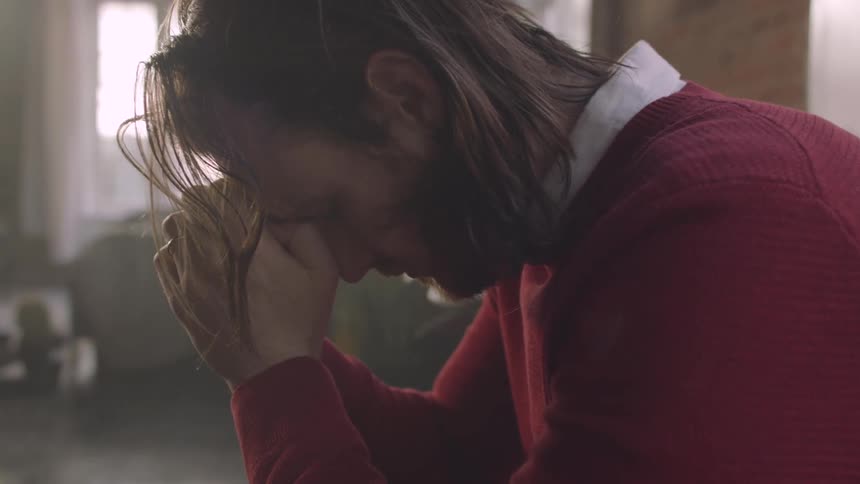 The man is sitting with his head resting on his hands