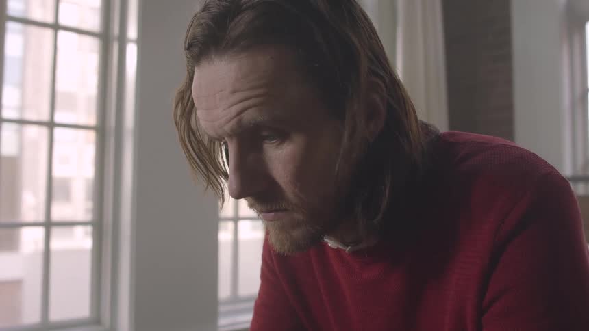 A man looks sad while sitting in bed
