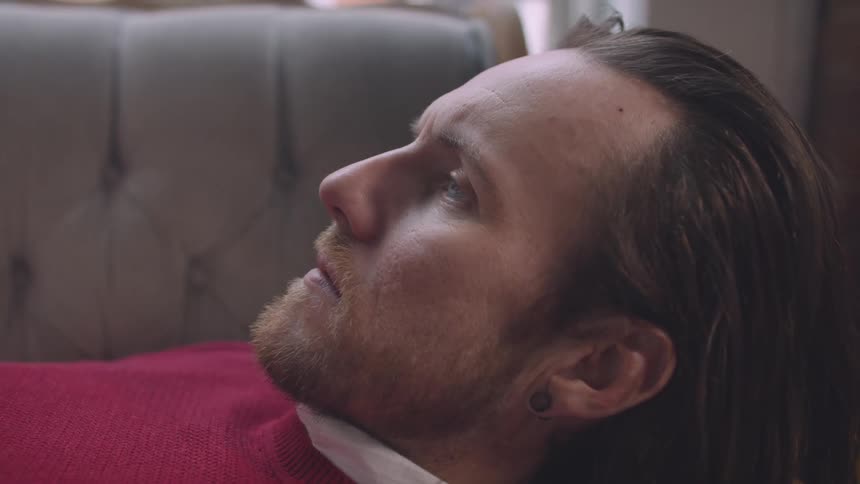 A facial clip of a man laying on the couch