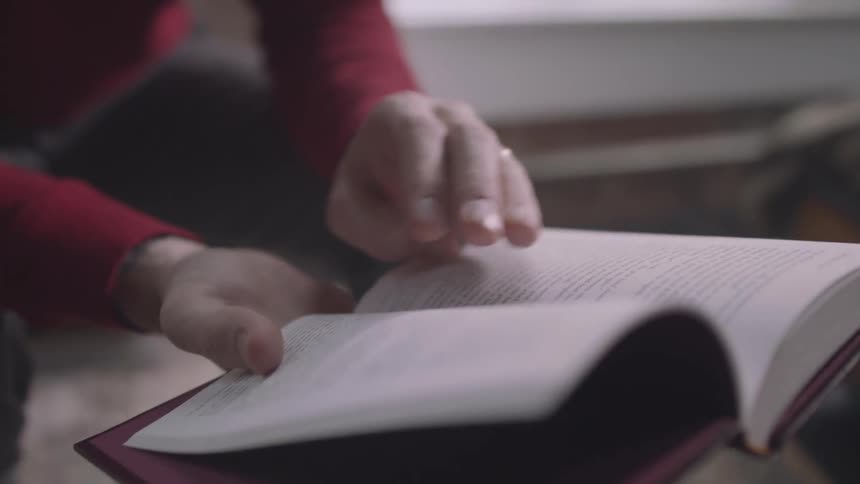 Closeup on the hands of an elderly man reading a book