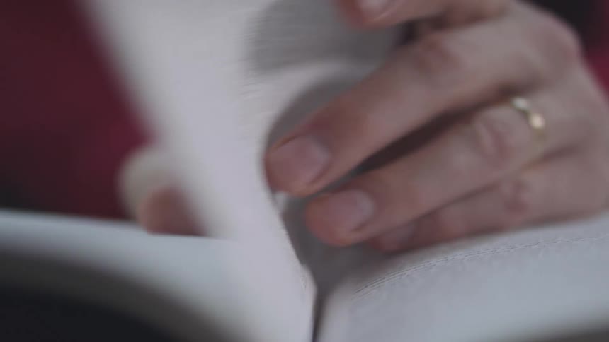 A persons hands turning the pages of a book