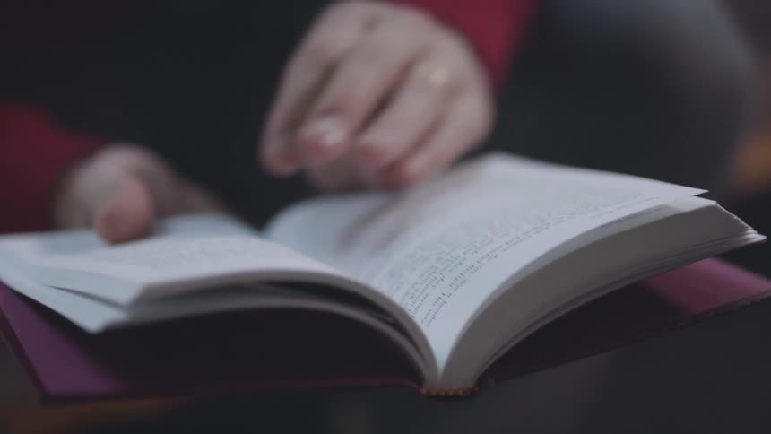 A persons hands turn the pages of an open book
