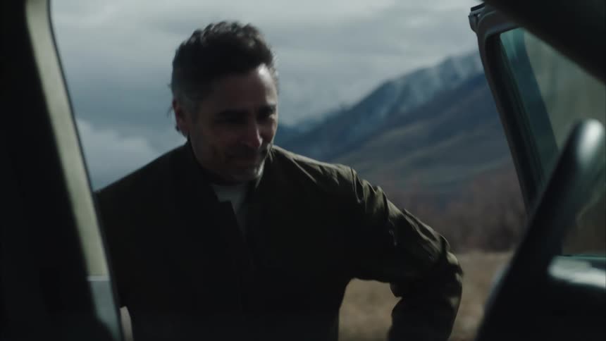A man walks form the mountain and gets in the car