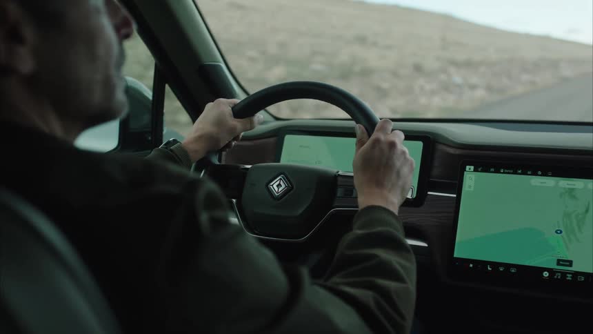 Man with both hands on the steering wheel driving a vehicle