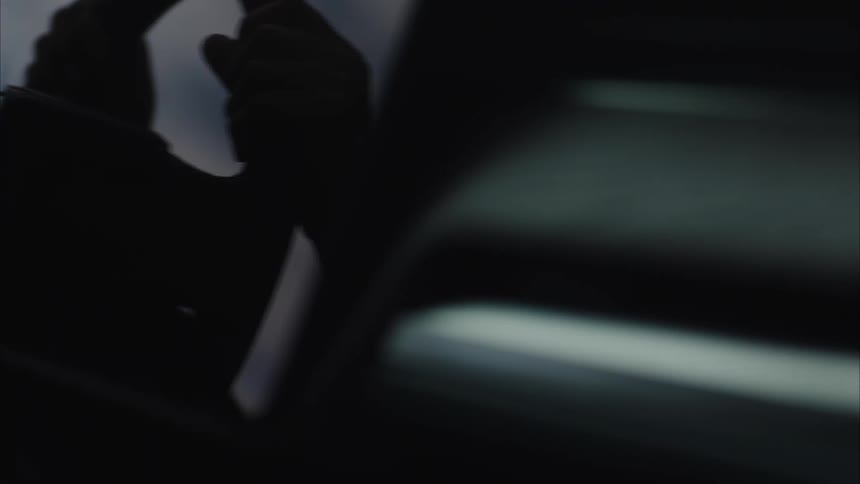A closeup reveals a dark textured surface with the word rivian subtly visible on a center door handle detail within the interior of a car