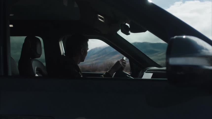 A man gets out of his van and walks towards the mountains