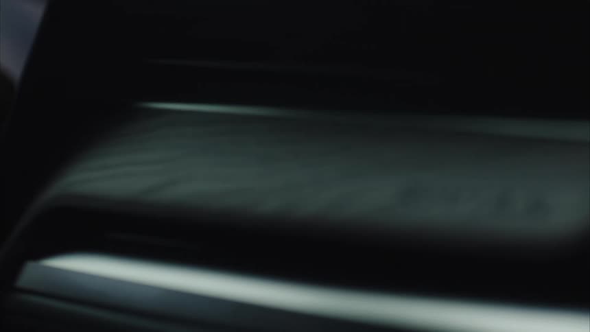 The hands of a man gripping a steering wheel are reflected on the cars dashboard