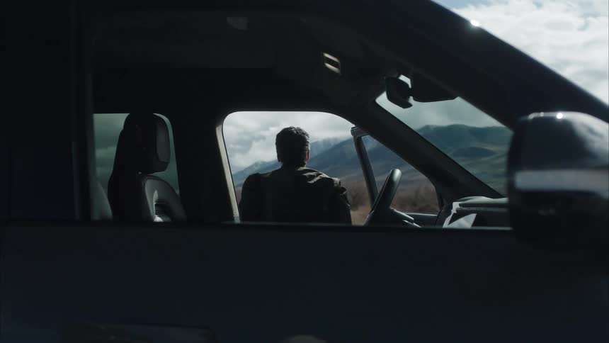 A man gets out of his car and walks on a windy day