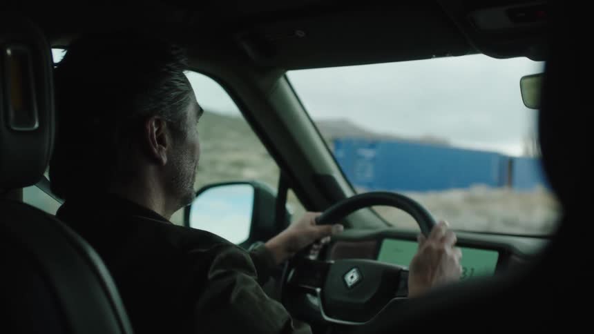 Man driving the car and talking to someone beside him