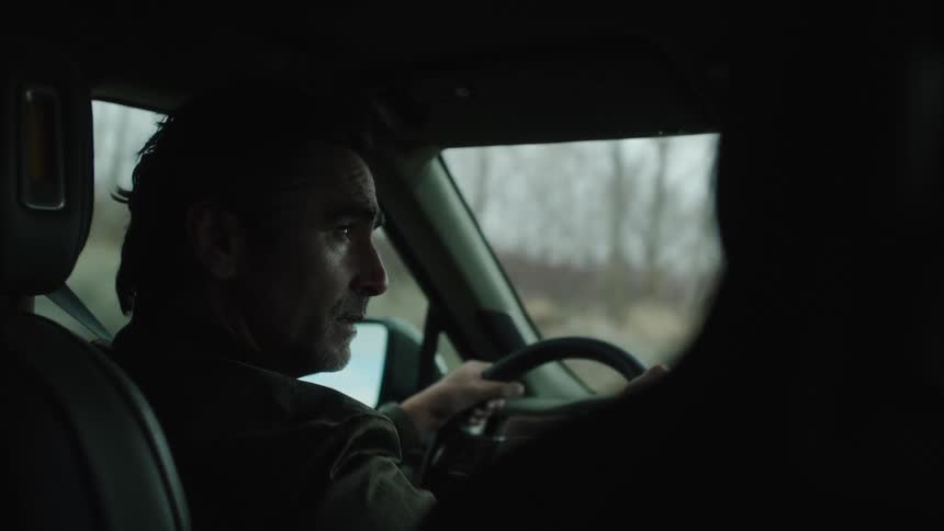 A man looks angry as he drives and talks to his passenger