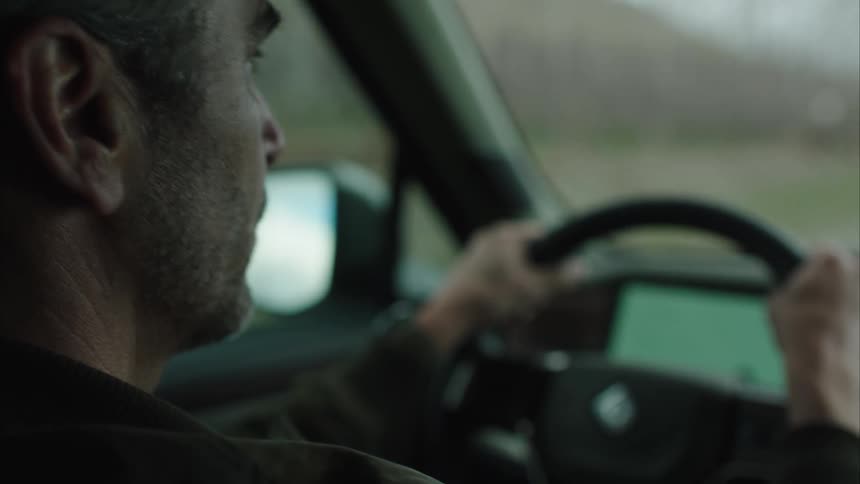 A man looks to his side and smiles while driving