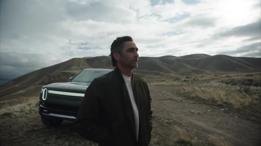 A man is standing by his vehicle near the mountain