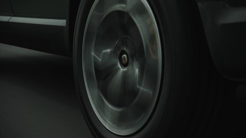 A car wheel in motion with the spinning hubcap in sharp focus